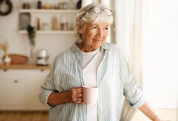 Senior woman looking out window while drinking tea