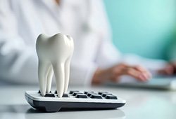 A fake tooth standing on top of a calculator
