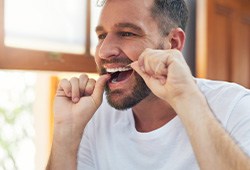 Man smiling while flossing his teeth
