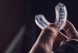 Fingers holding a clear mouthguard
