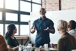 Man presenting information to co-workers in front of whiteboard