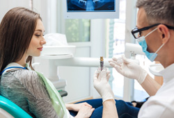 Dentist showing sample dental implant to patient in dental chair