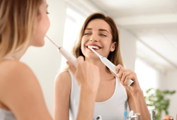 Woman brushing teeth with electric brush