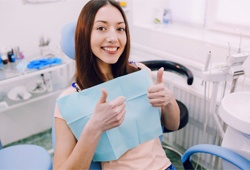 Smiling woman in the dental chair giving thumbs up