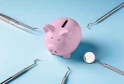 Dental tools surrounding a piggy bank on a blue background