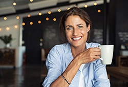 smiling woman holding a white coffee mug