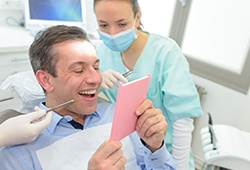 dental implant patient admiring his new smile in a mirror