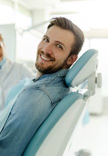 Man in denim shirt smiling during dental checkup