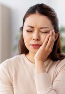 Closeup of woman in pink shirt struggling with toothache