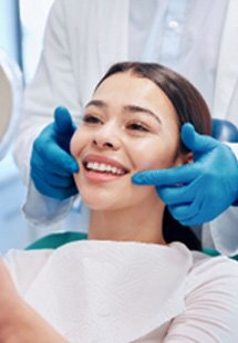 Woman smiling at reflection in dentist's mirror