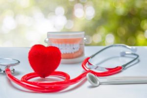 Small heart shape, stethoscope, model teeth, and dental tools on table 