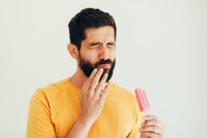 Pained man with sensitive teeth and a popsicle