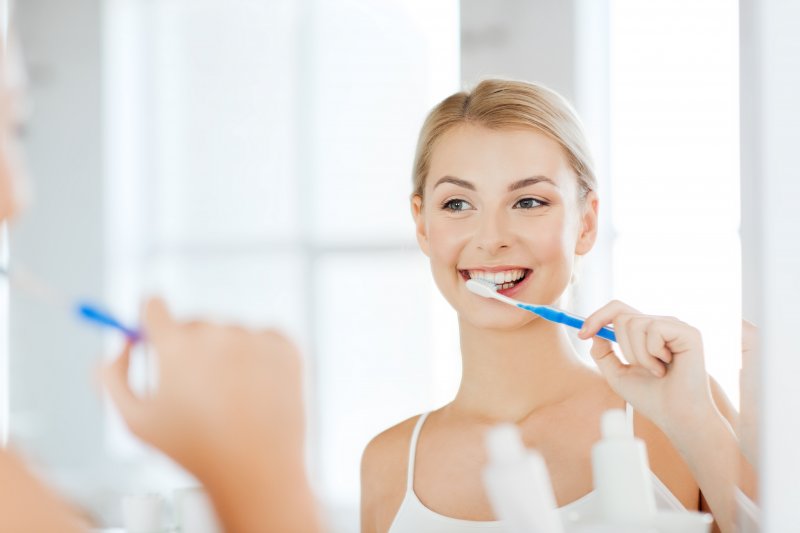 Woman smiling while brushing her teeth