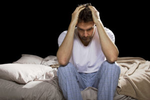 Man unable to sleep holding head in hands