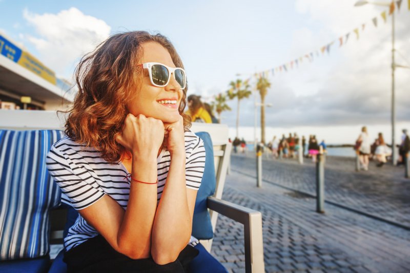 Woman smiling while sitting by the water