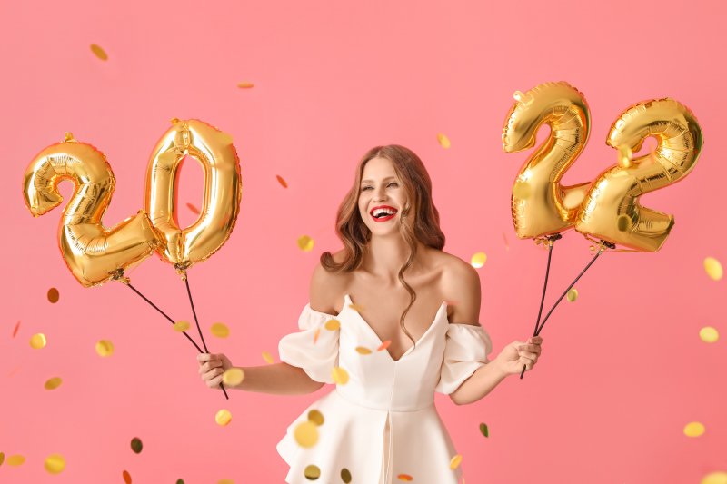 person holding up 2022 New Year’s balloons