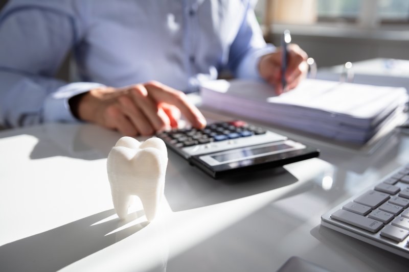 Businessperson calculating expenses near model tooth