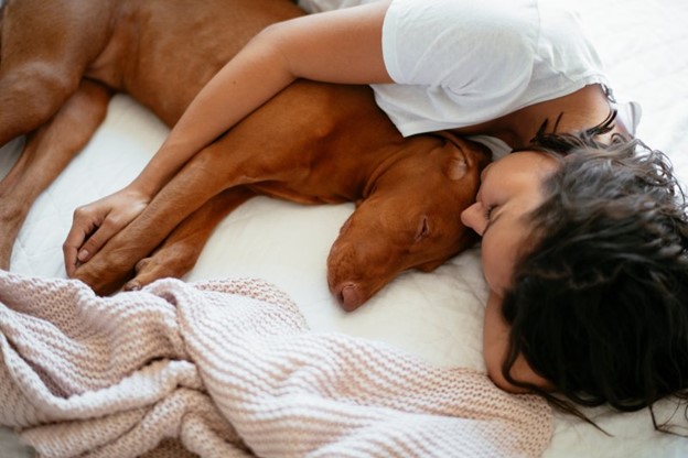 Woman sleeping next to dog.