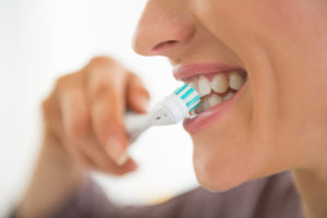 Closeup on young woman brushing teeth on white background