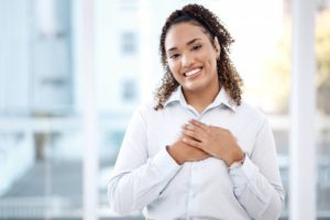 a woman smiling and placing her hands over her heart