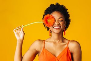 a woman with a refreshed smile holding a spring flower