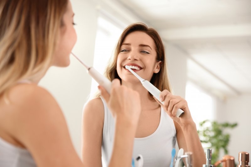 A woman brushing her teeth to remove plaque for good oral health